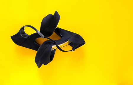 Stylish black velvet shoes with high heels on bright yellow backgroundの写真素材