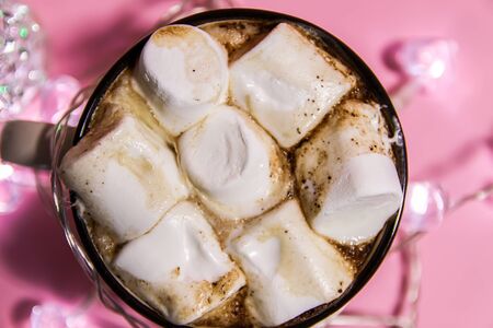 Ceramic mug with hot fresh cocoa drink with melting sweet marshmallow on soft pink background.