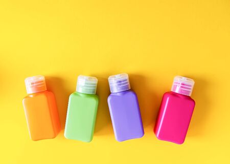 Colorful plastic bottles for skincare products on bright yellow backgroundの写真素材