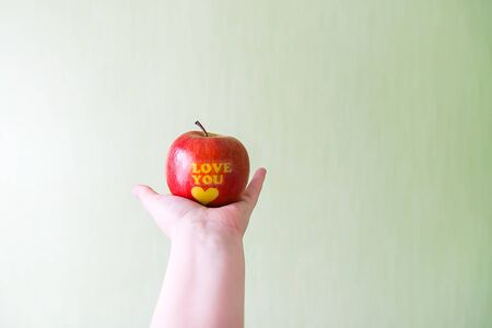 Fresh red apple in hand with words I love you and heart.の写真素材