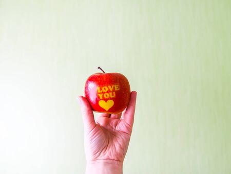 Fresh red apple in hand with words I love you and heart.