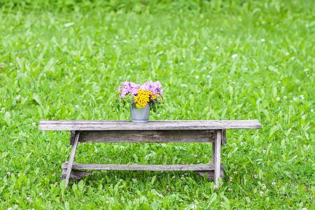 Beautiful bouquet of wildflowers on wooden bench on summer nature background in countryside.の写真素材