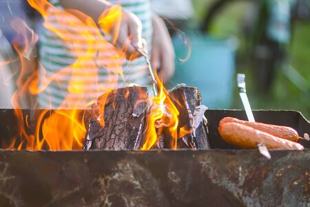 Child preparing marshmallow on wooden stick over a brazier