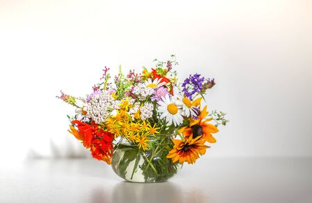 Beautiful bouquet of summer wildflowers in a transparent vase on white background.の写真素材
