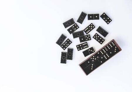 Heap of vintage black domino tiles and dominoes in the box on light background.の写真素材