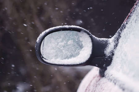 Car wing mirror covered up with fresh wet snow.の写真素材