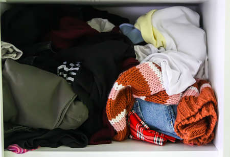 Home wardrobe with different clothes. Small space organization. Disorder. Vertical storage boxの写真素材