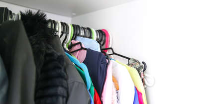 Colorful clothes hanging on hangers at the home wardrobe. Small space organisation.