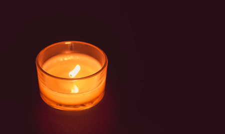 Burning candle hot flame in glass candlestick.