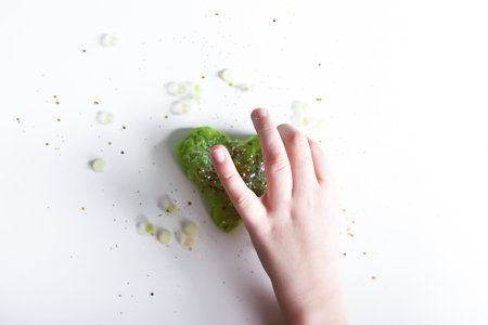 Green heart with shiny glitters made from slime by child