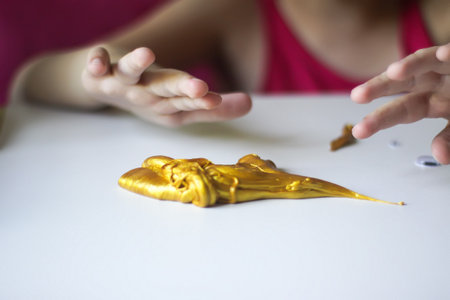 Little girl playing with the gold slime. Sensory activity for child.の写真素材
