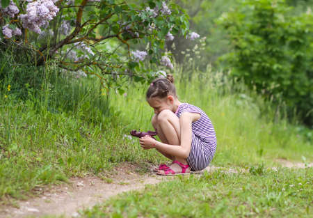 Little girl in striped dress playing with the plastic dinosaur toy in spring parkの写真素材