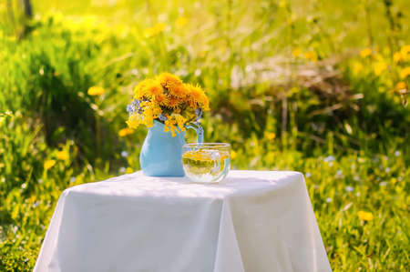 Bouquet of dandelion flowers on small table in spring garden in sunny dayの写真素材
