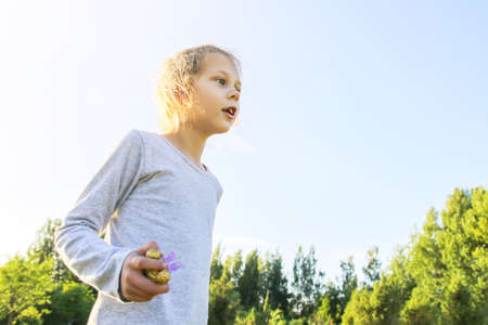 Happy little girl with her toy walks outdoors in summer sunny day.