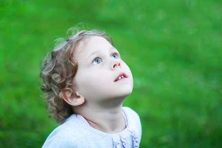 Little adorable girl looking at the sky outdoors.の写真素材
