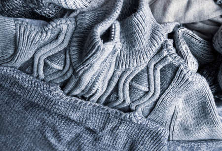 Warm knitted textile stack with the different texture in grey color palette close up.