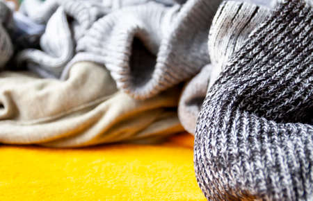 Warm knitted jumpers and sweaters on bright yellow background.