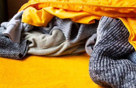Warm knitted grey jumpers and sweaters on bright yellow background.の写真素材
