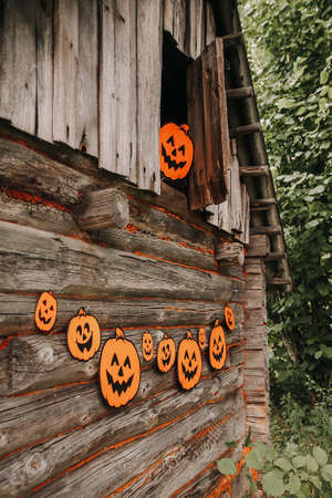 Halloween decor outdoors. Paper pumpkins on wooden building of the bathhouse in village.の写真素材