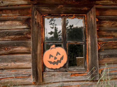 Paper pumpkin pumpkin on the wooden window of the old bathhouse. Halloween decor outdoors.の写真素材