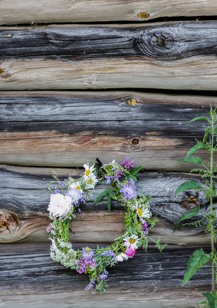 Wreath of wildflowers hanging on the weathered wooden wall. Floral decor in rustic style.の写真素材