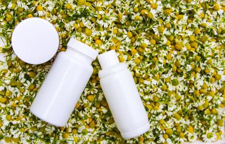 White plastic containers and Chamomile flowers for cosmetic products, herbal tea or treatment.の写真素材