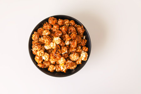 Sweet ready-to-eat popcorn in a black ceramic plate close up.の写真素材