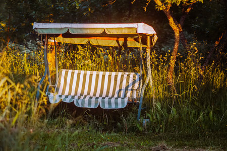 Swing in the garden. Garden furniture made of metal and striped canvas.の写真素材