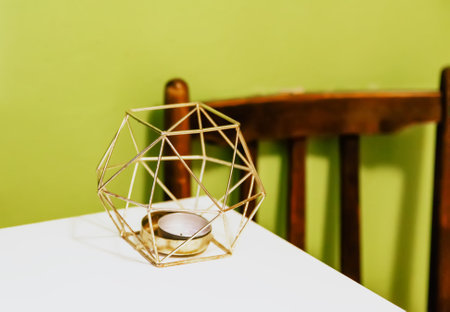 Modern metal candlestick on the white table in room interior.