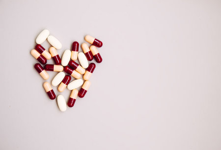 Heart-shaped pills on light background. Medicine theme.