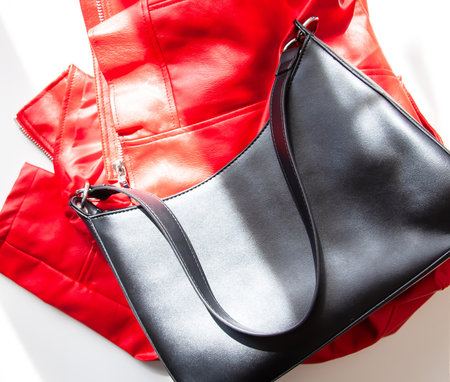 Black leather fashion bag and red jacket on a white background.の写真素材