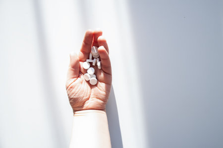 Assorted pills in a hand under diffused light. Aesthetic representation of healthcare and wellness.の写真素材