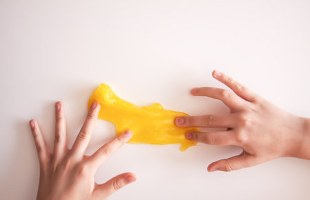 Small hands squeezing colorful slime. Suggests sensory fun and early learning.の写真素材