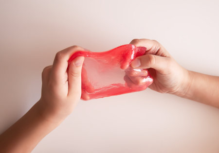 Small hands squeezing colorful slime. Suggests sensory fun and early learning.の写真素材