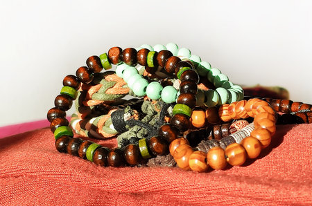 Colorful beaded bracelets rest on a soft textile in warm light. It represents harmony, handcrafted quality, and slow fashion.の写真素材