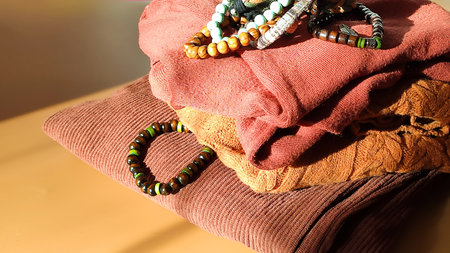 Vibrant bracelets made of wood contrast with a cozy fabric surface. The scene reflects creativity,...