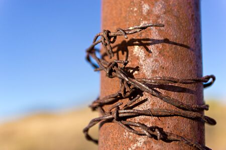 Barbed wire wrapped around iron postの写真素材