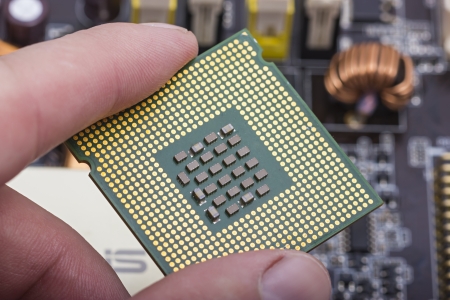 Computer microprocessor held between fingersの写真素材