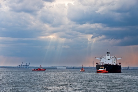 Maneuvers at sea on a cloudy day - Escorting tanker by tugs.の写真素材