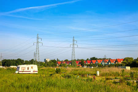 A line of electricity pylons in the meadows near the houses の写真素材