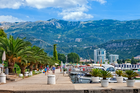 Unknown people walking on the promenade of Slovenska Obala with boats and palm trees in port of Budva, Montenegro.のeditorial素材