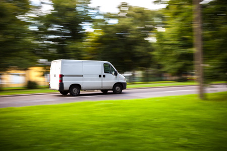 White delivery van speeding on road with blurred countryside panorama in background.の写真素材