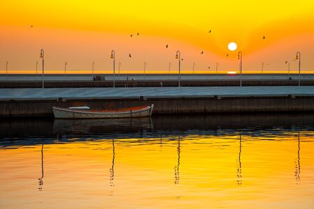 Picturesque landscape of a sunrise with a boat on a pier in Sopot, Poland.の写真素材