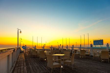 Bar chairs and tables in early morning light with sea views and the pier, on April 10, 2015 in Sopot, Poland.のeditorial素材