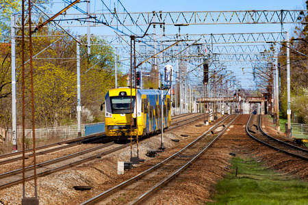 Yellow blue train on the track moving through in Poland.