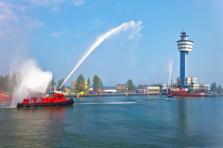 Fire fighting boat sprays water in port.の写真素材