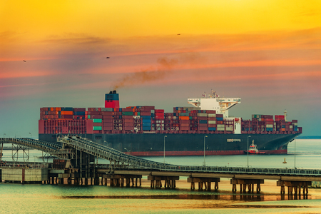 Tugboat assisting container ship on sea in the morning.の写真素材