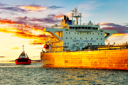 Tanker and tugboat on sea early morning just before sunrise.の写真素材