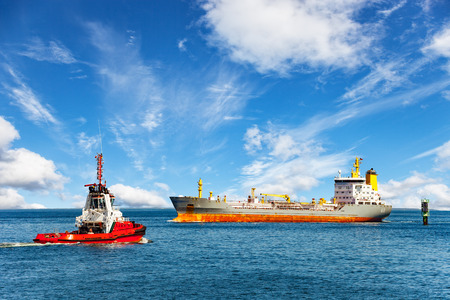 Red tug boat approaching to assist tanker.の写真素材