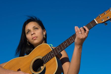 Ethnic female guitarist with blue sky background